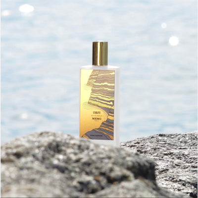 Philadelphia Boutique Spa, French Perfume, MEMO PARIS, Corfu eau de parfum bottle on a rock in front of water, Victoria Roggio Beauty, Philadelphia Perfumes, Luxury Fragrances